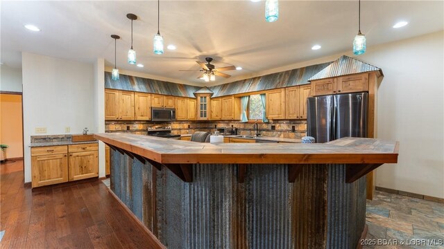 kitchen with decorative backsplash, appliances with stainless steel finishes, a sink, baseboards, and butcher block countertops