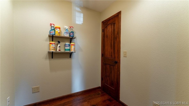 corridor featuring baseboards and dark wood finished floors