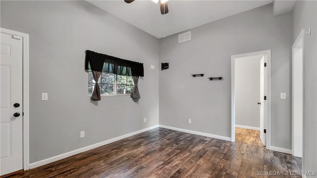 spare room featuring dark wood-style flooring, a ceiling fan, baseboards, and visible vents