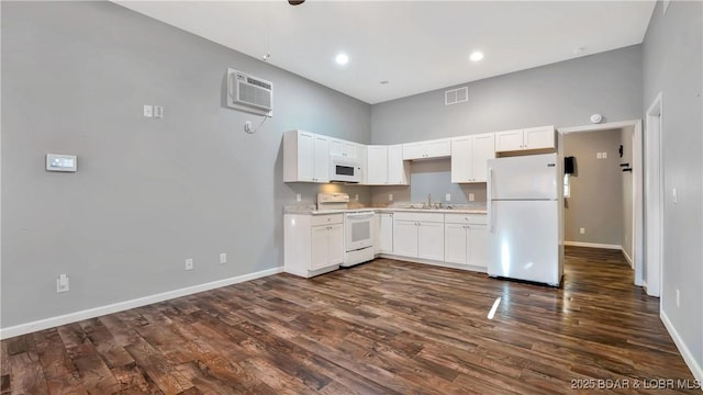 kitchen featuring visible vents, a towering ceiling, white appliances, baseboards, and a sink