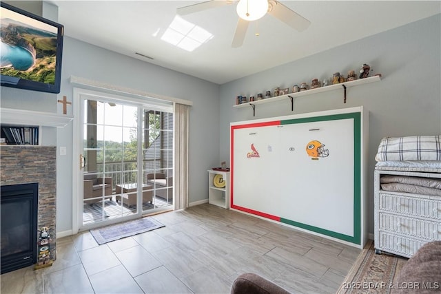 doorway to outside with a stone fireplace, baseboards, ceiling fan, and visible vents