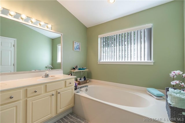 bathroom featuring vaulted ceiling, vanity, and a garden tub