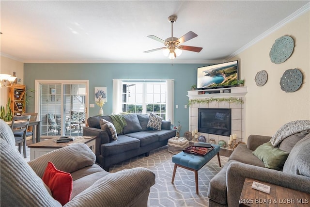 living room with crown molding, ceiling fan, and a tiled fireplace