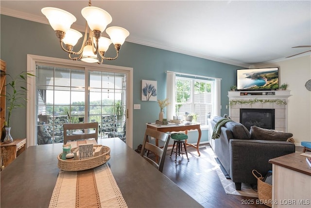 dining space featuring ornamental molding, a tile fireplace, wood finished floors, and a notable chandelier