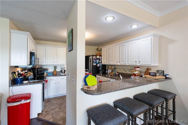 kitchen with white cabinets, stainless steel appliances, and a kitchen breakfast bar