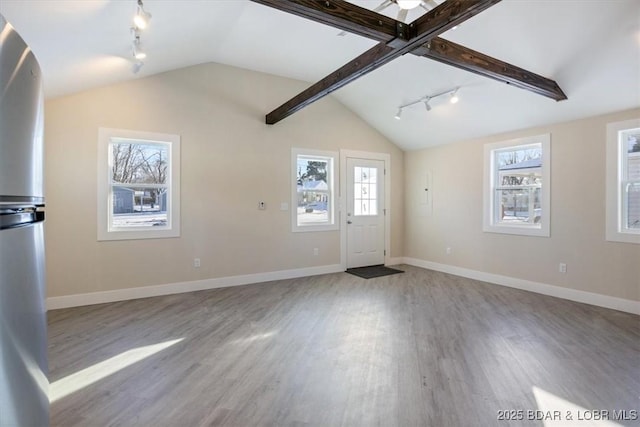 unfurnished living room with track lighting, baseboards, wood finished floors, and lofted ceiling