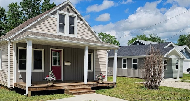 bungalow with roof with shingles, a porch, and a front yard