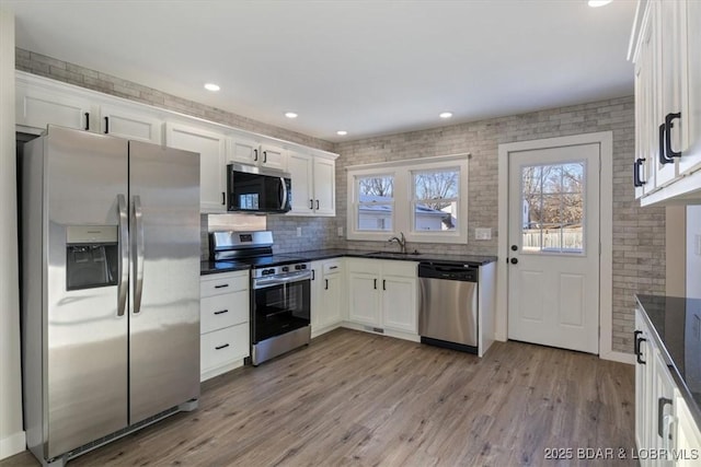 kitchen with a healthy amount of sunlight, white cabinets, appliances with stainless steel finishes, and a sink
