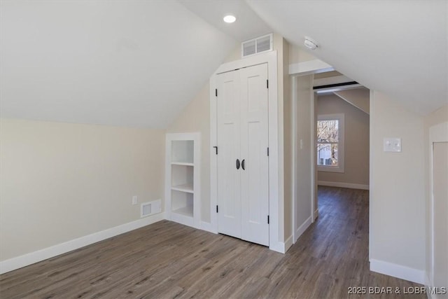 additional living space featuring vaulted ceiling, visible vents, and wood finished floors