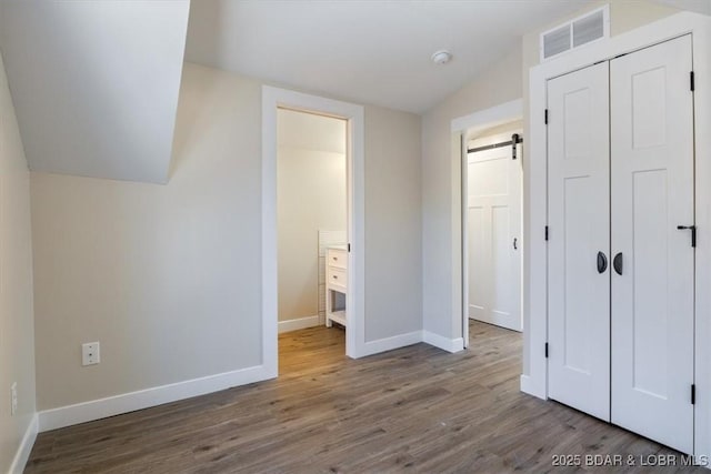 421 W High St, Eldon, MO 65026 - unfurnished bedroom featuring vaulted ceiling, baseboards, wood finished floors, a closet, and connected bathroom