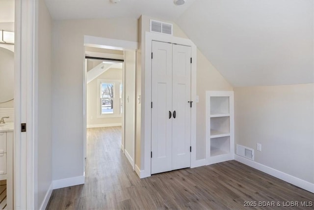bonus room featuring baseboards, visible vents, wood finished floors, and lofted ceiling
