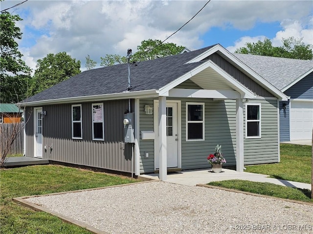 view of front of property featuring a shingled roof, an attached garage, and a front lawn