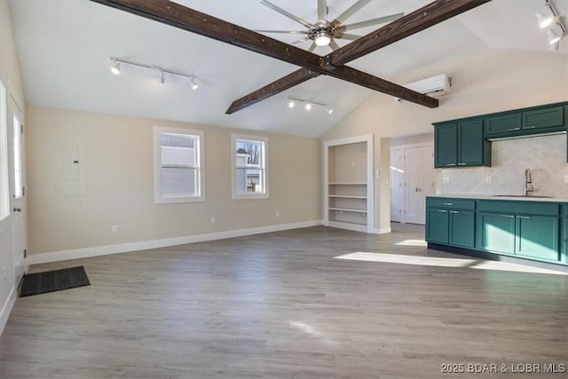 unfurnished living room with a sink, track lighting, and lofted ceiling with beams