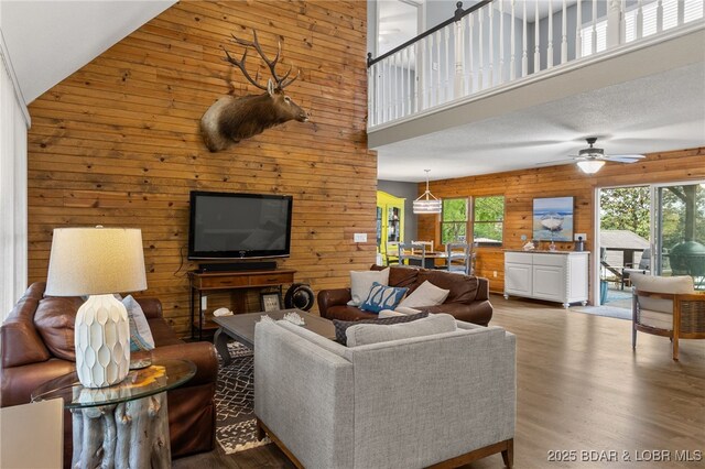 20168 Lost Valley Rd, Warsaw, MO 65355 - living area with a high ceiling, wood walls, healthy amount of natural light, a ceiling fan, and wood finished floors