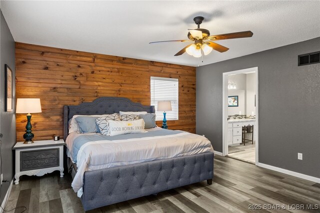 20168 Lost Valley Rd, Warsaw, MO 65355 - bedroom with wooden walls, wood finished floors, ceiling fan, ensuite bath, and baseboards