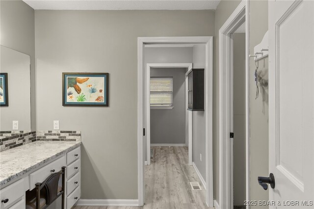 20168 Lost Valley Rd, Warsaw, MO 65355 - bathroom with wood finished floors, vanity, backsplash, and baseboards