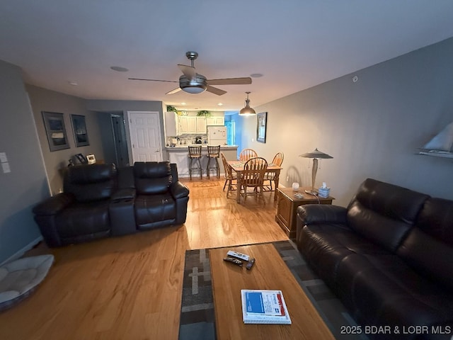 living area with ceiling fan and light wood-type flooring