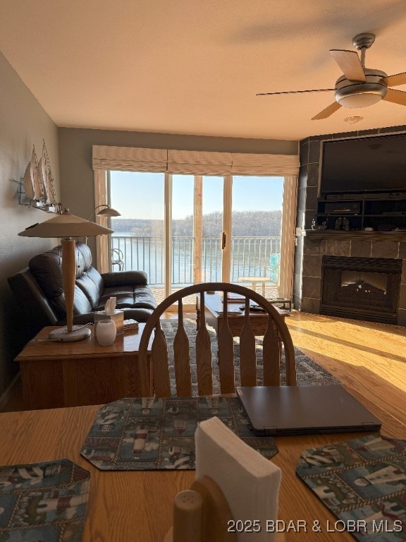 dining space with ceiling fan, wood finished floors, and a fireplace