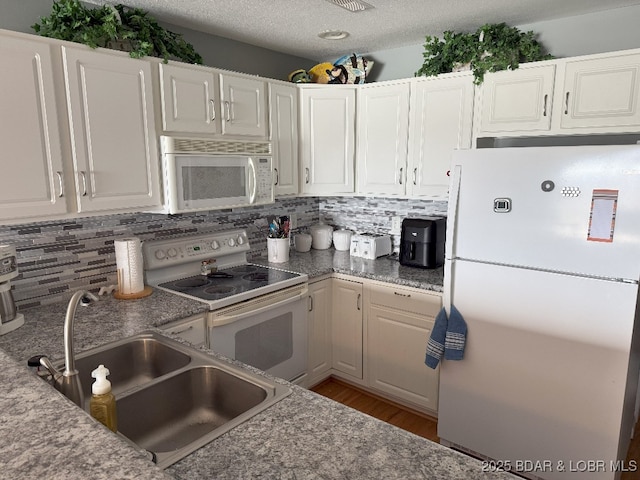 kitchen featuring a sink, tasteful backsplash, white appliances, and white cabinets