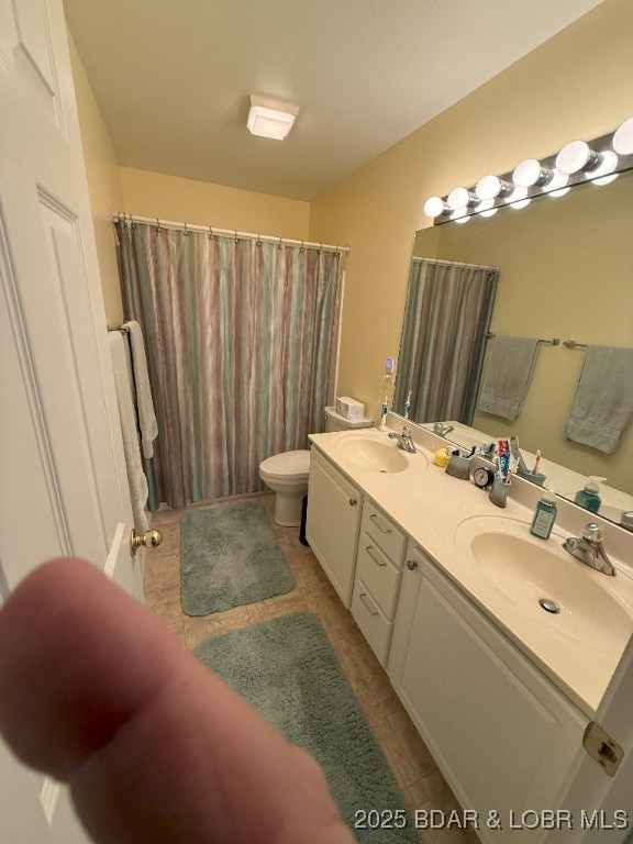 bathroom featuring tile patterned flooring, a sink, double vanity, and toilet