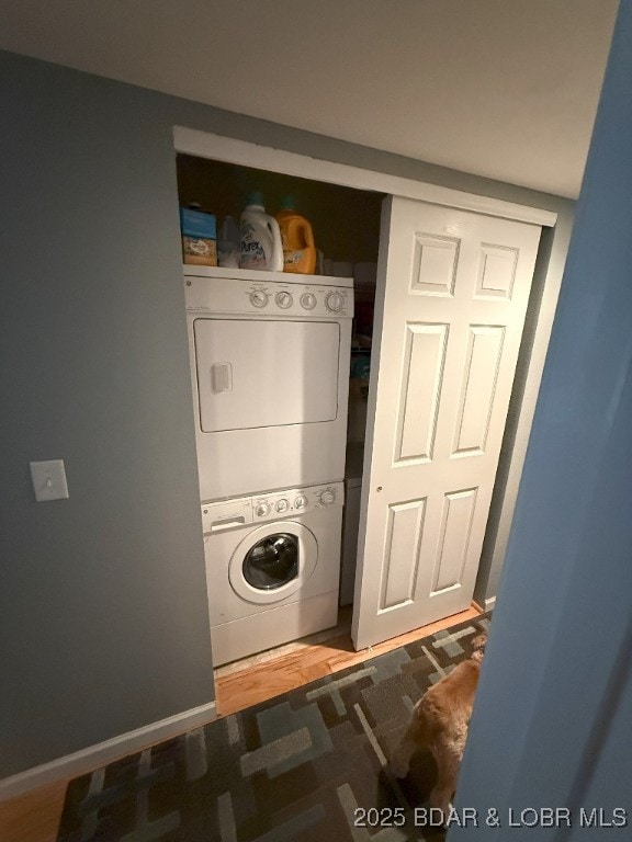washroom with laundry area, baseboards, and stacked washer / dryer