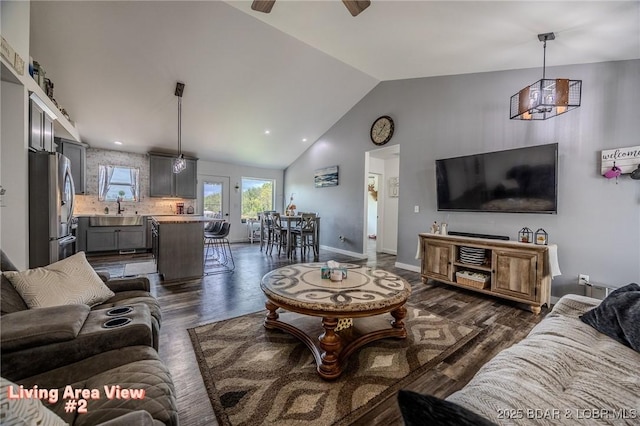 living area featuring a ceiling fan, high vaulted ceiling, baseboards, and dark wood-type flooring