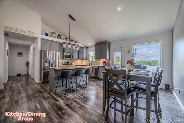 dining area featuring visible vents, dark wood-style flooring, baseboards, recessed lighting, and vaulted ceiling
