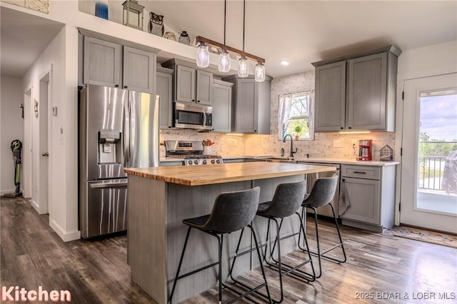 kitchen with dark wood-style flooring, wooden counters, a center island, stainless steel appliances, and backsplash