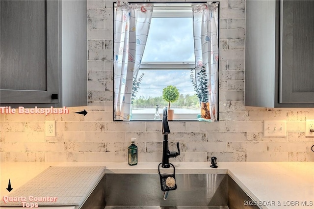 interior details featuring light countertops, tasteful backsplash, gray cabinets, and a sink