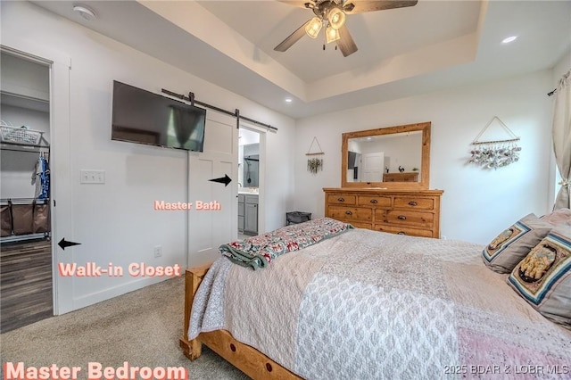 carpeted bedroom featuring a ceiling fan, a barn door, a raised ceiling, baseboards, and recessed lighting