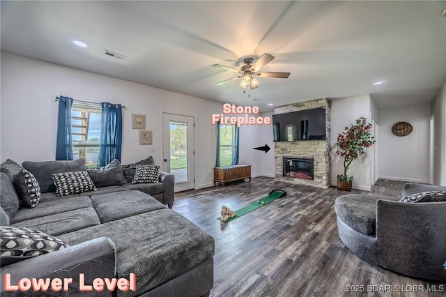 living room featuring visible vents, a fireplace, baseboards, ceiling fan, and dark wood-type flooring
