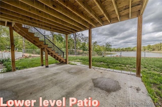 view of patio with a water view, fence, and stairway