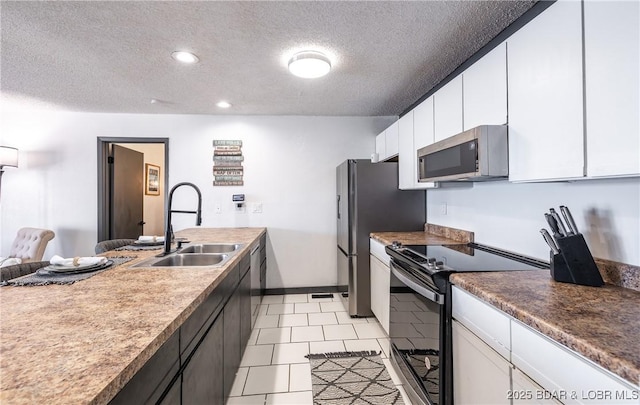 kitchen featuring a sink, stainless steel appliances, a textured ceiling, recessed lighting, and white cabinets