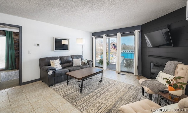 living area featuring a textured ceiling, visible vents, baseboards, and light tile patterned floors