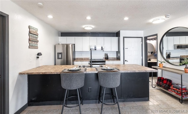 kitchen with stainless steel appliances, white cabinetry, a peninsula, a kitchen breakfast bar, and light countertops