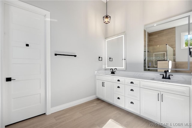 full bathroom with double vanity, wood finished floors, tiled shower, and a sink