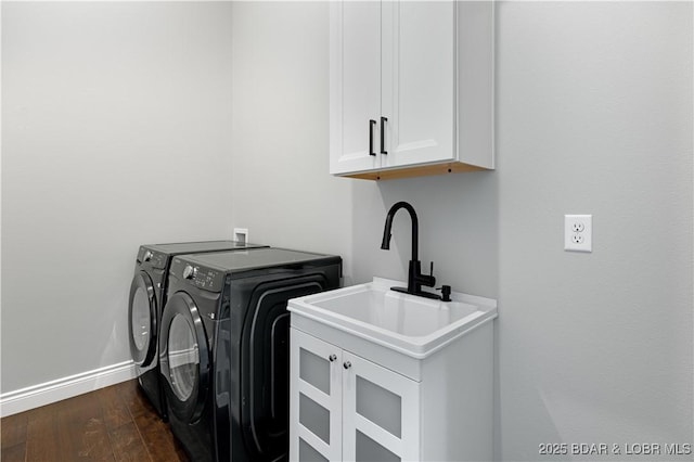clothes washing area with independent washer and dryer, baseboards, a sink, cabinet space, and dark wood-style floors