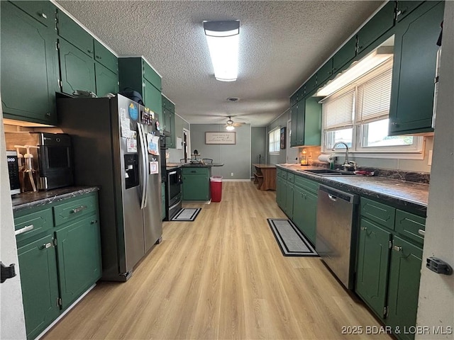 kitchen featuring a ceiling fan, a textured ceiling, green cabinets, light wood finished floors, and appliances with stainless steel finishes