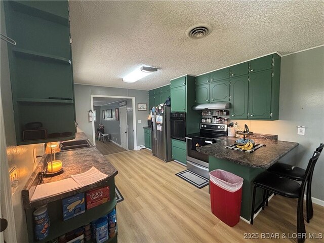 kitchen featuring under cabinet range hood, light wood-style floors, stainless steel appliances, and a peninsula