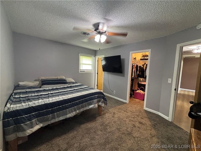 bedroom with carpet flooring, a closet, a walk in closet, visible vents, and ceiling fan