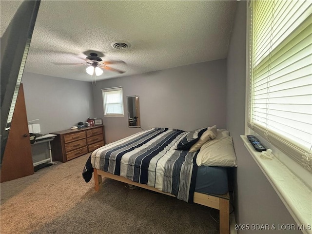 carpeted bedroom with a textured ceiling, visible vents, and ceiling fan