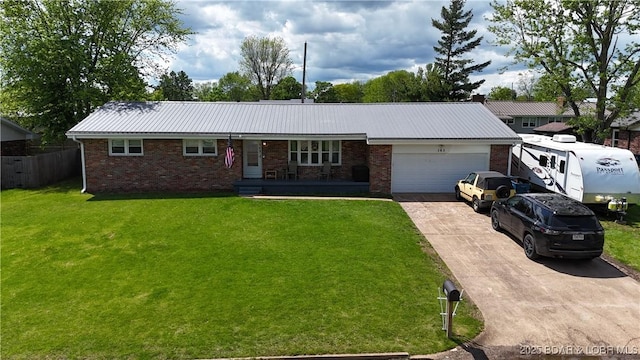 single story home featuring an attached garage, metal roof, a front yard, brick siding, and driveway