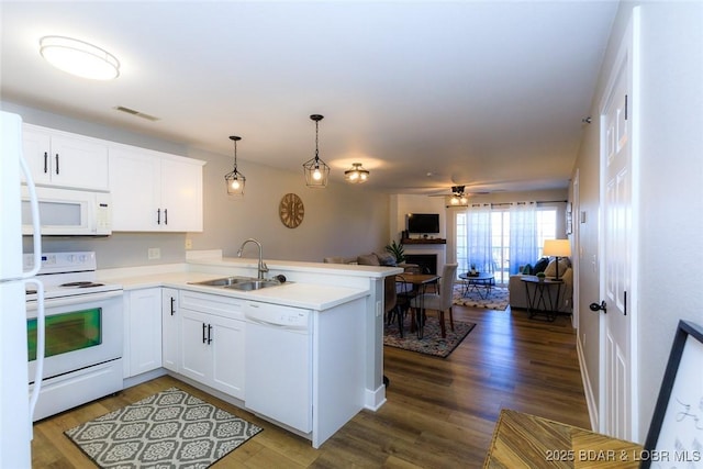 kitchen featuring white appliances, visible vents, a sink, a peninsula, and open floor plan