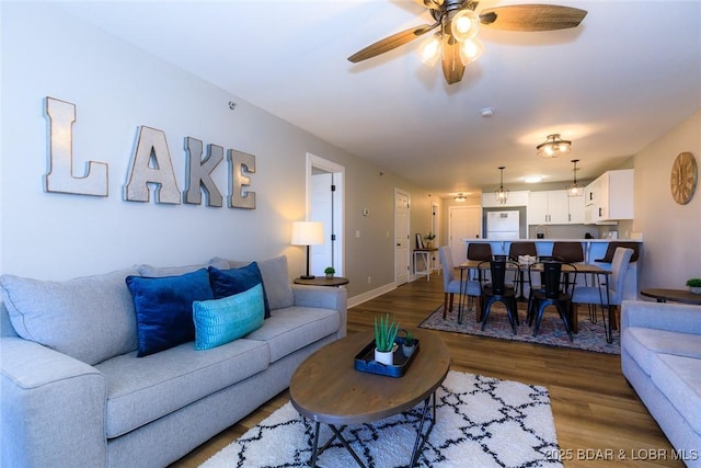 living area featuring baseboards, wood finished floors, and a ceiling fan