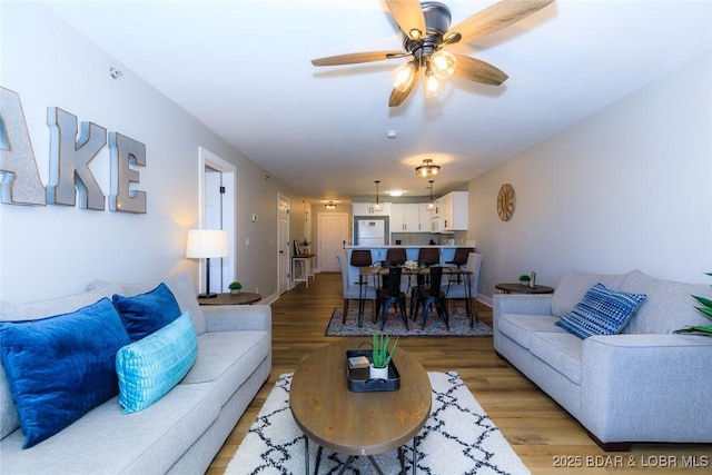 living area featuring ceiling fan, baseboards, and light wood-style floors