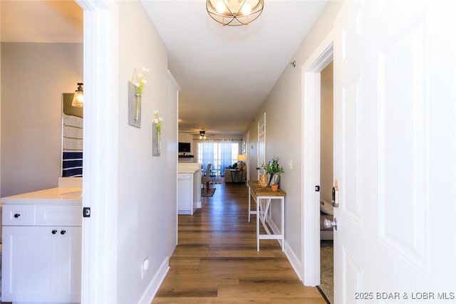 hall with light wood-style flooring and baseboards