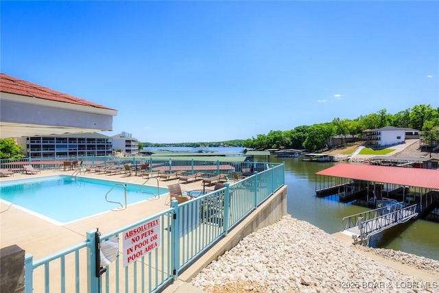community pool featuring fence, a water view, and a patio