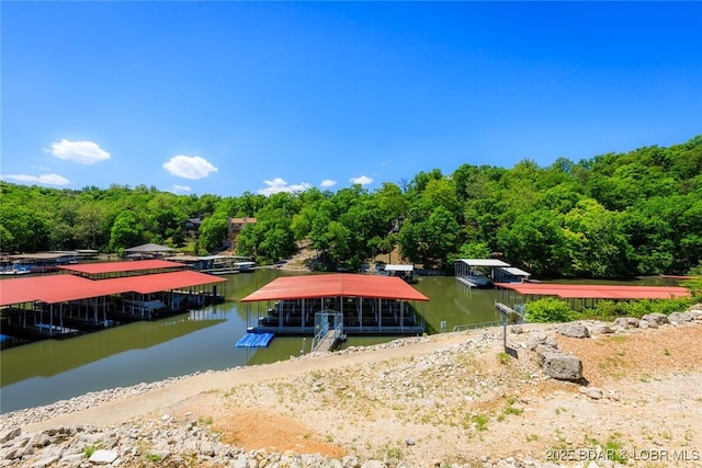 view of dock featuring a wooded view and a water view