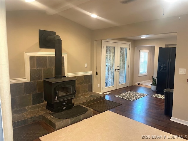 interior space featuring a wood stove, french doors, wood-type flooring, and vaulted ceiling with beams