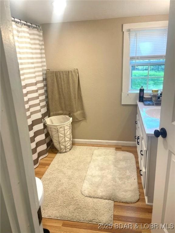 full bathroom featuring curtained shower, baseboards, wood finished floors, and vanity